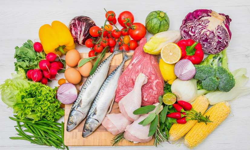 Botella de aceite de oliva virgen extra junto a verduras y hierbas frescas mediterráneas